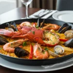 Paella de marisco gourmet con bogavante, gambas, mejillones y almejas sobre arroz dorado